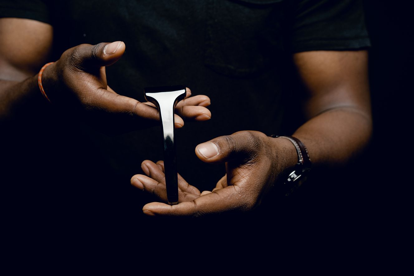 Person holding a SE Razor between their hands against a dark background