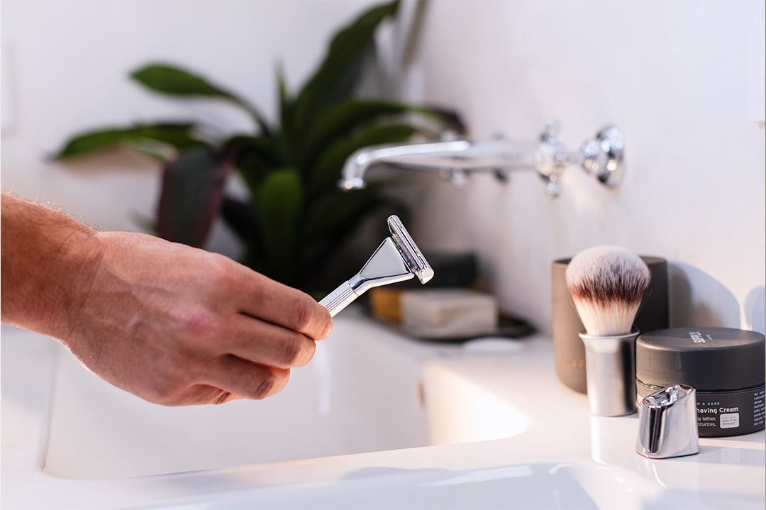 man picking up Single Edge Max razor in bathroom